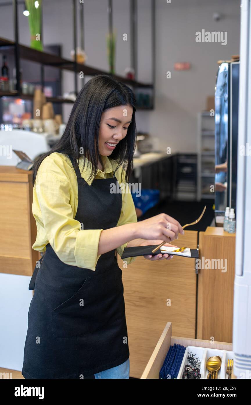 Femme tenant des couverts debout sur le lieu de travail Banque D'Images
