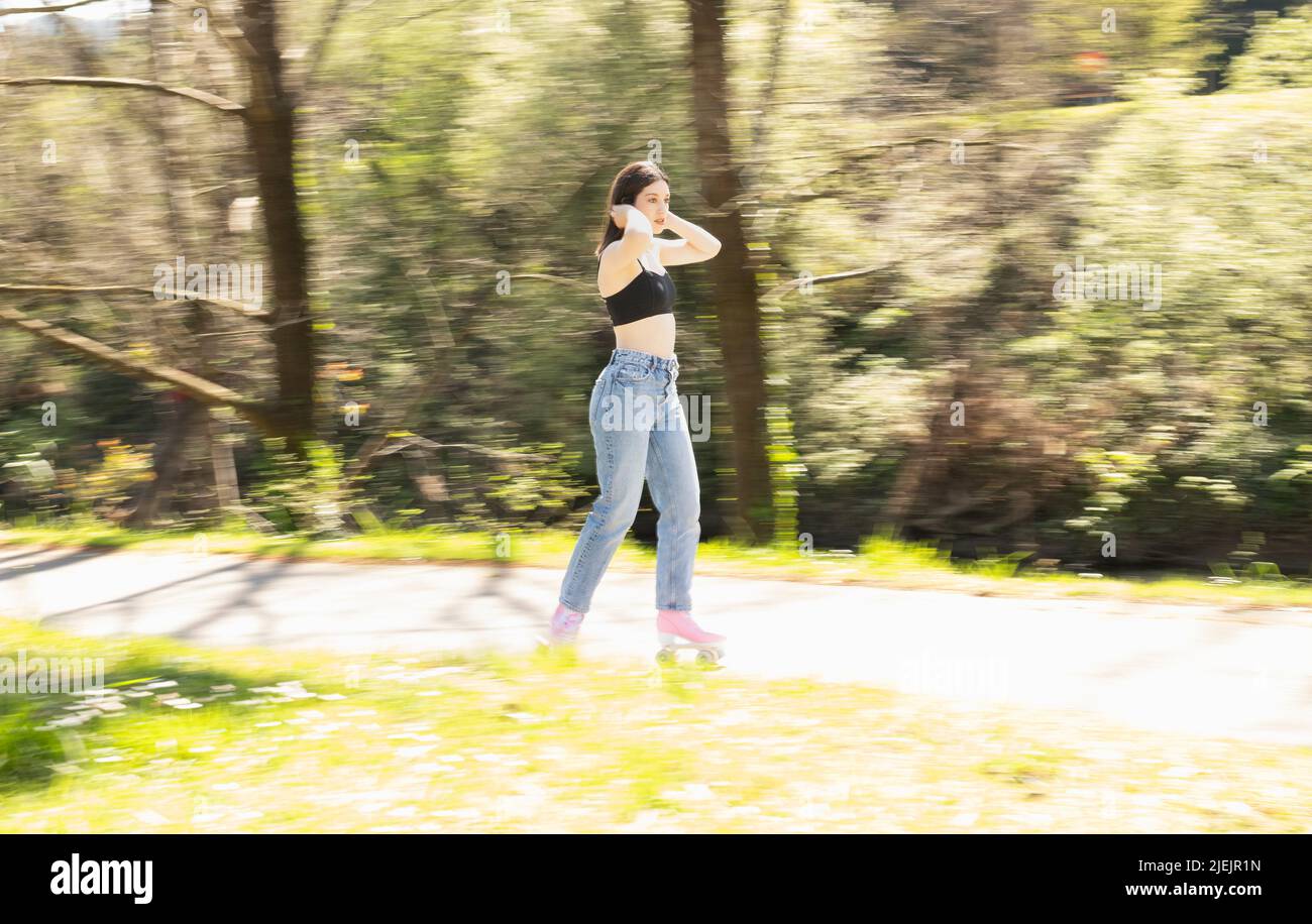 brunette femme patinant dans un parc avec des patins à roulettes roses Banque D'Images