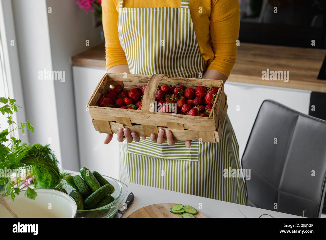 Femme courte tenant une boîte en bois de fraise à côté de la table de cuisine. Une alimentation saine par une nouvelle recette pour un corps mince. Cuisson Banque D'Images