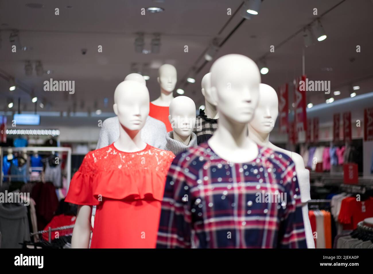 Les mannequins féminins sont vêtus de vêtements décontractés avec un thème rouge-orange dans la boutique de mode du grand magasin. Banque D'Images