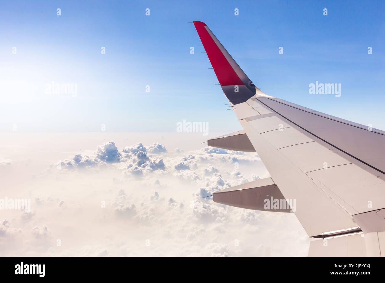 Les ailes d'avion et les grappes de nuages blancs dans le ciel bleu et la lumière du soleil sont de beaux paysages, utilisés pour les illustrations et les images de fond de commer Banque D'Images