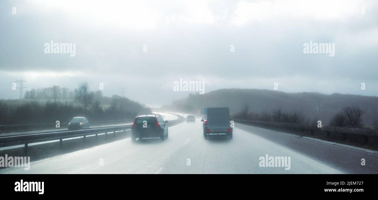 Voitures à la distance de rupture sur une autoroute par temps pluvieux au Danemark. Véhicules à moteur roulant sur une route asphaltée dangereuse lors d'une journée d'hiver froide et brumeuse dans un Banque D'Images