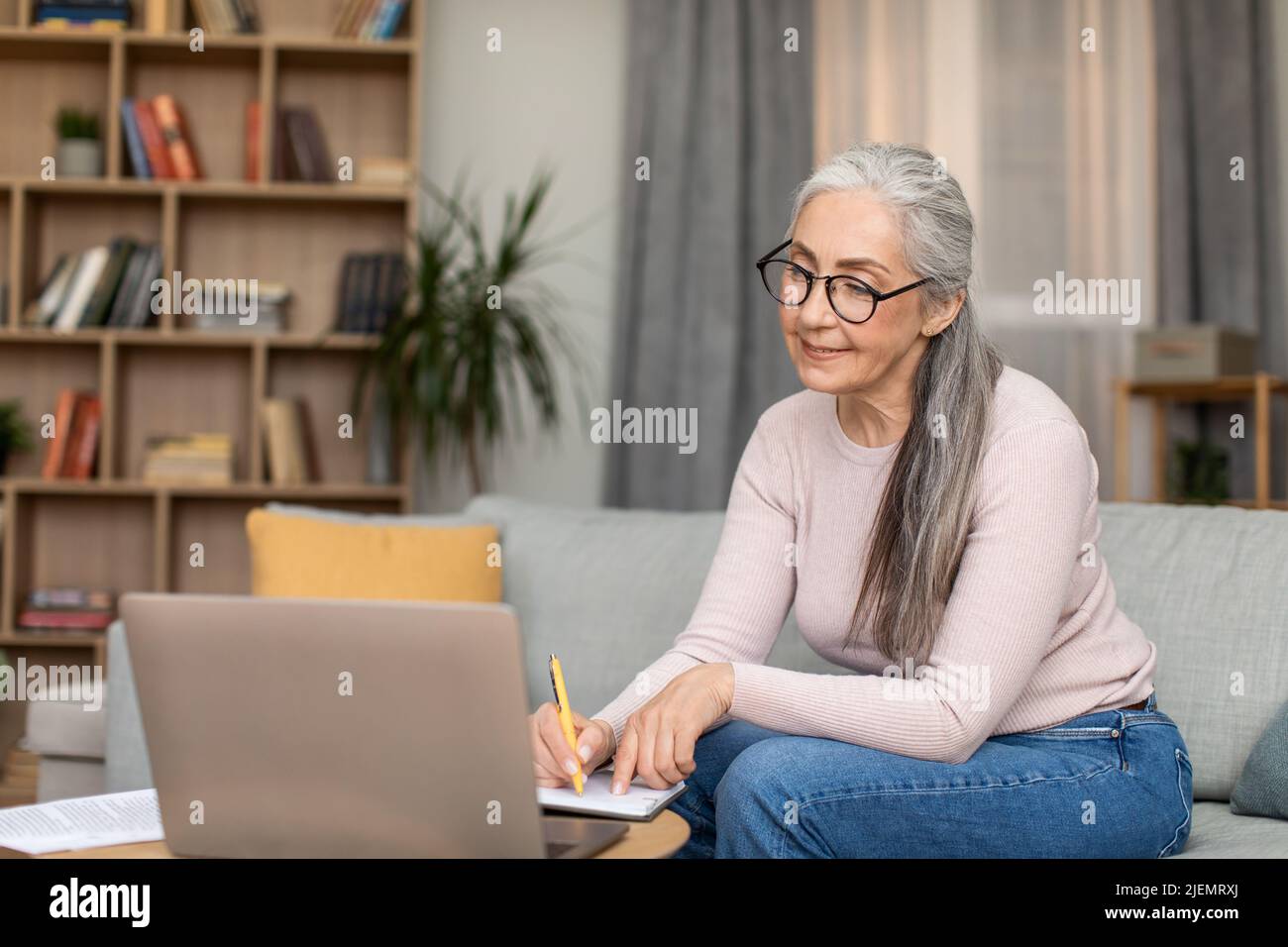 Professeur de femme mature européenne concentrée avec des cheveux gris dans les verres travaille avec l'ordinateur, ont la réunion à distance Banque D'Images