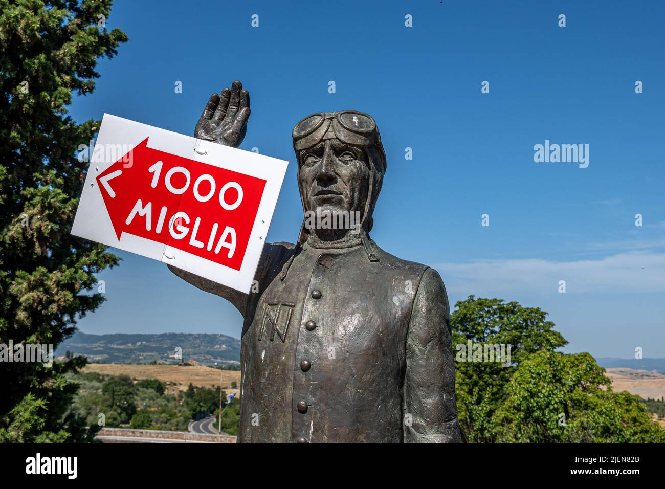 La statue commémorative de Tazio Nuvolari avec un panneau publicitaire de la course de route mille Miglia, San Quirico d'Orcia, Toscane, Italie Banque D'Images
