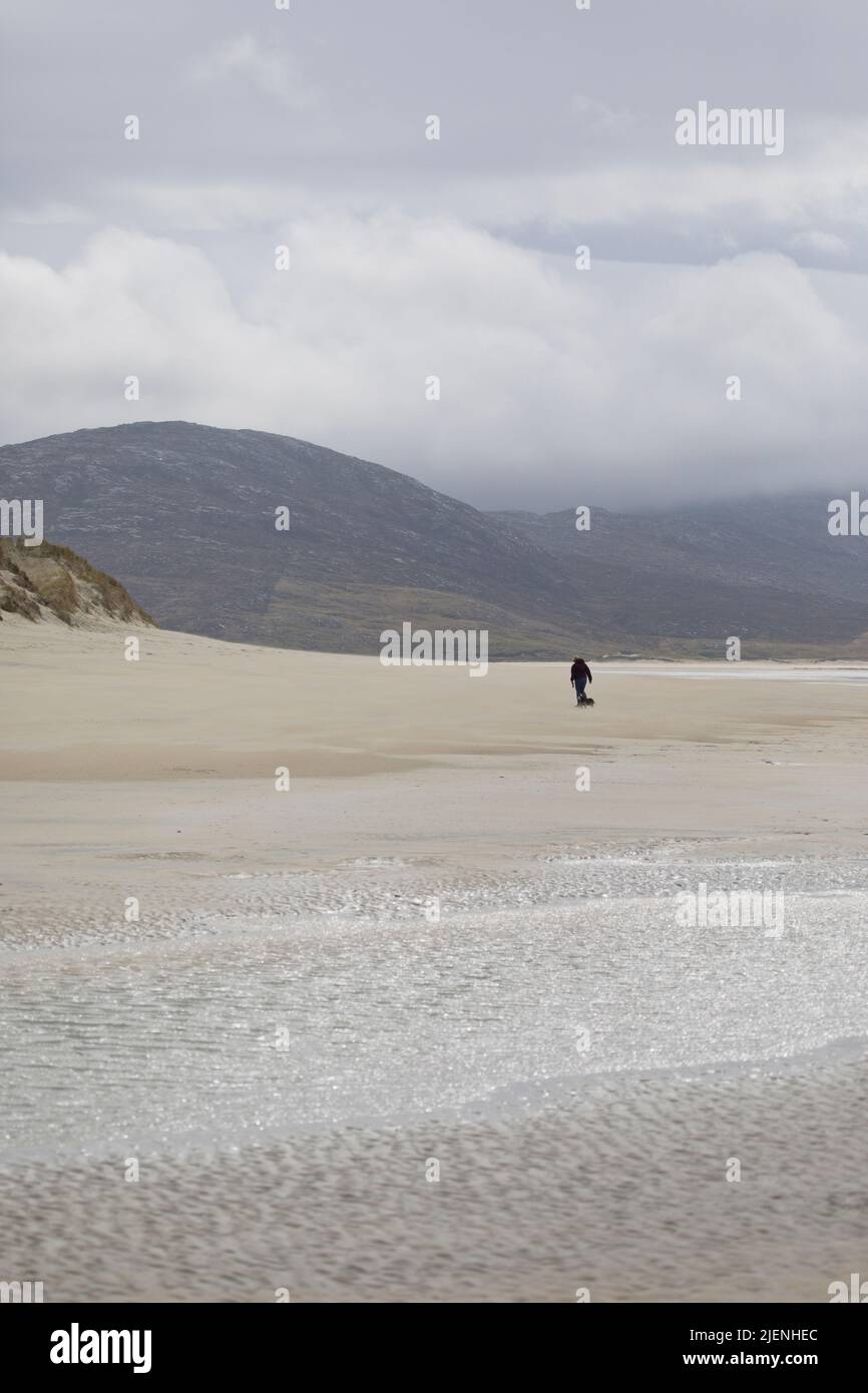 Femme emportant son chien pour une promenade à la plage de LUSKENTIRE sur l'île de Harris, Outer Hebrides, Écosse, Royaume-Uni Banque D'Images