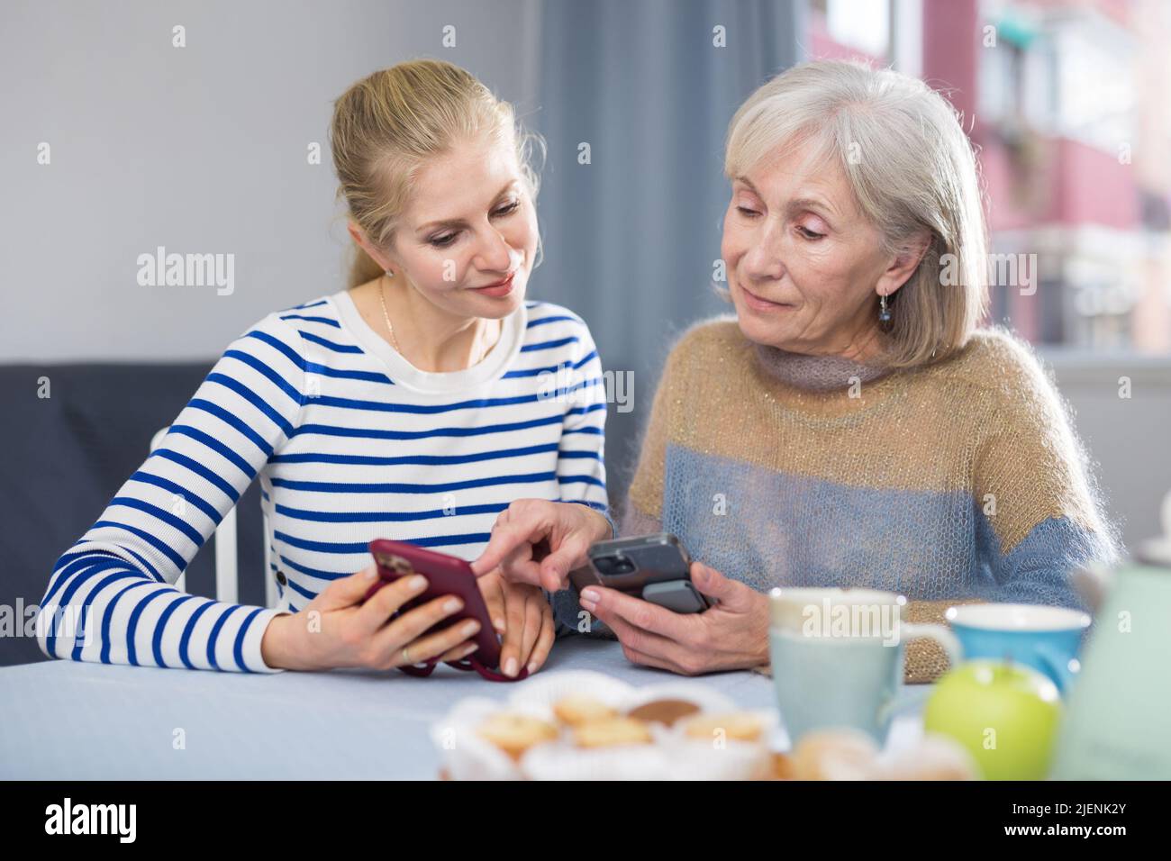 Femme adulte avec sa fille adulte regardant des photos sur un téléphone portable Banque D'Images
