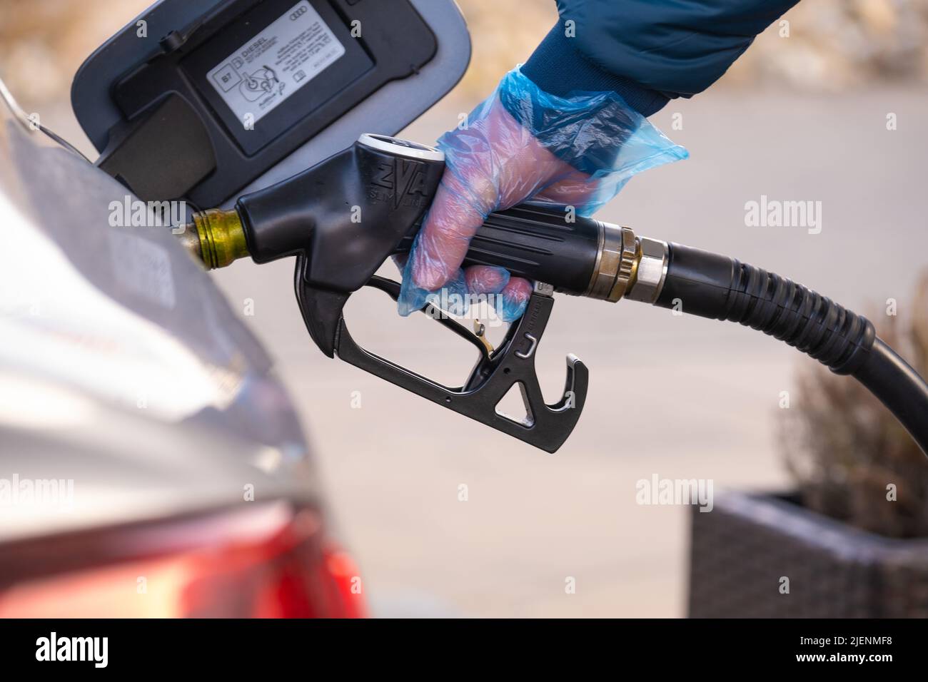 Diesel.Prix du carburant en Europe. Ravitaillement de la voiture.pistolet de ravitaillement dans les mains d'un homme dans un gant bleu.voiture à une station-service. Voiture argent, ravitaillement Banque D'Images