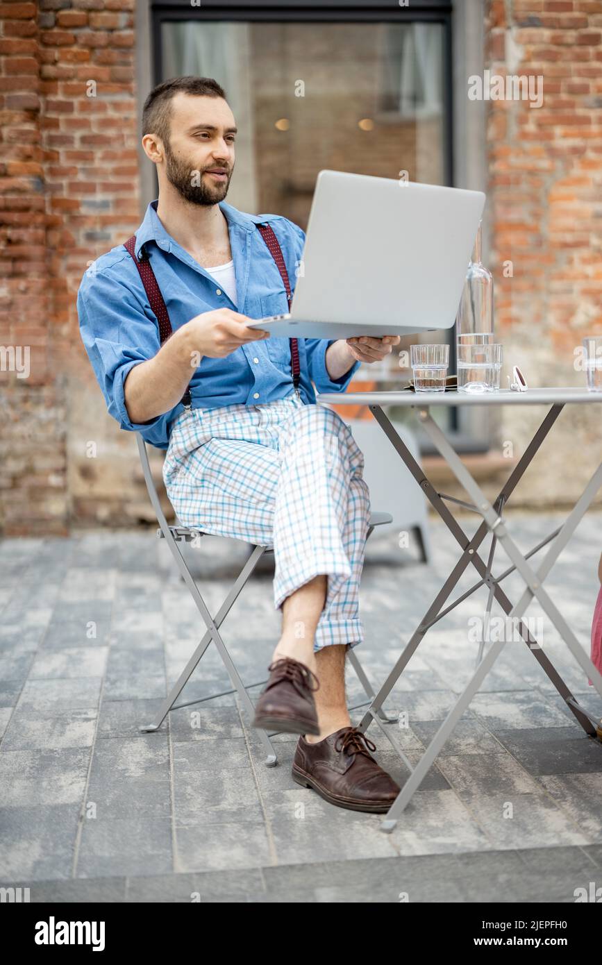 Un homme d'affaires élégant a une conversation en ligne sur ordinateur portable au café Banque D'Images