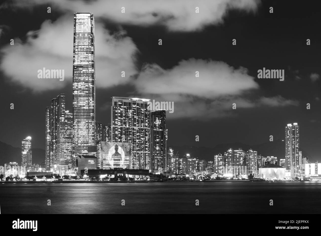 Le front de mer de Hong Kong West Kowloon s'illumine la nuit, dominé par le International Commerce Centre. Une longue exposition donne une mer douce comme de la soie. Banque D'Images