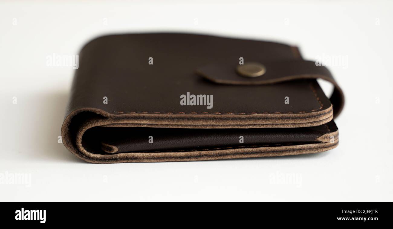 Vue latérale du nouveau portefeuille en cuir véritable brun foncé avec billets et carte de crédit à l'intérieur isolés sur fond blanc. Banque D'Images