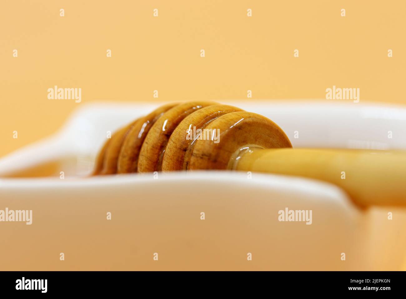 Miel biologique à partir d'une cuillère en bois sur l'assiette Banque D'Images