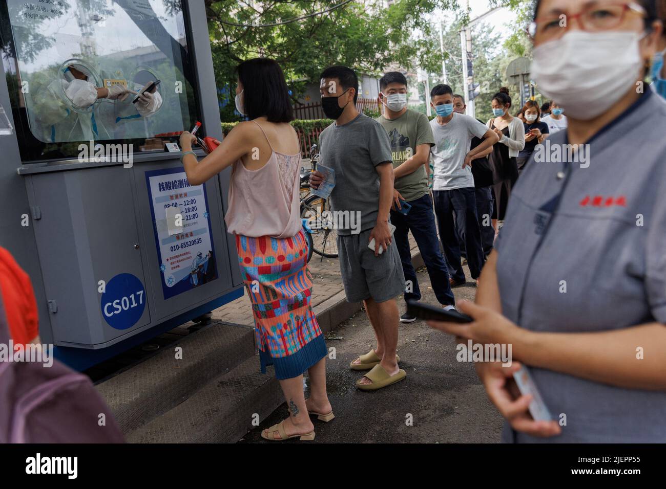 Les gens font la queue dans une station de dépistage des acides nucléiques, après l'éclosion de la maladie à coronavirus (COVID-19), à Beijing, en Chine, au 28 juin 2022. REUTERS/Thomas Peter Banque D'Images