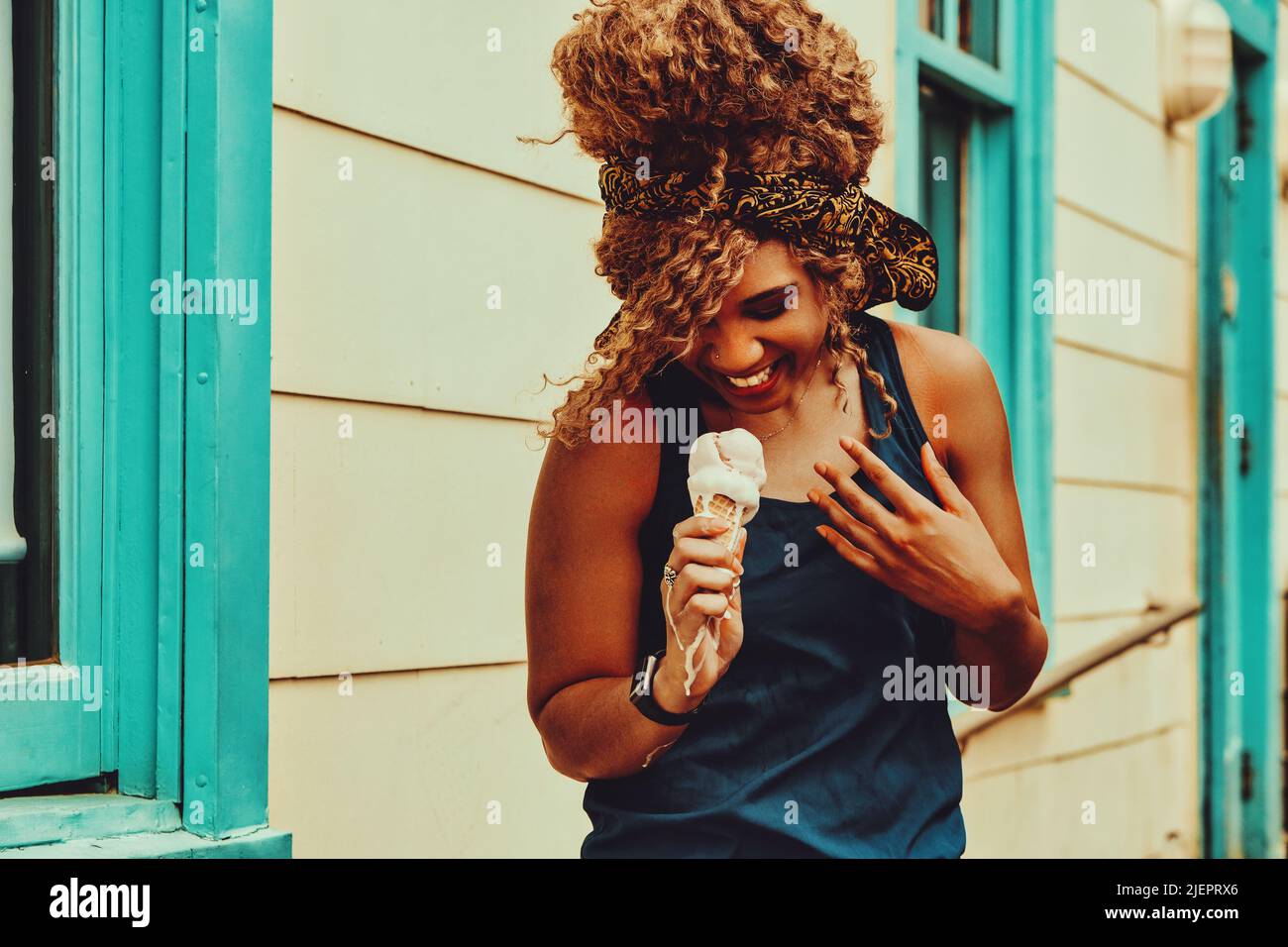 jeune femme adulte cheveux afro souriant manger de la glace à l'extérieur prise de vue estivale Banque D'Images