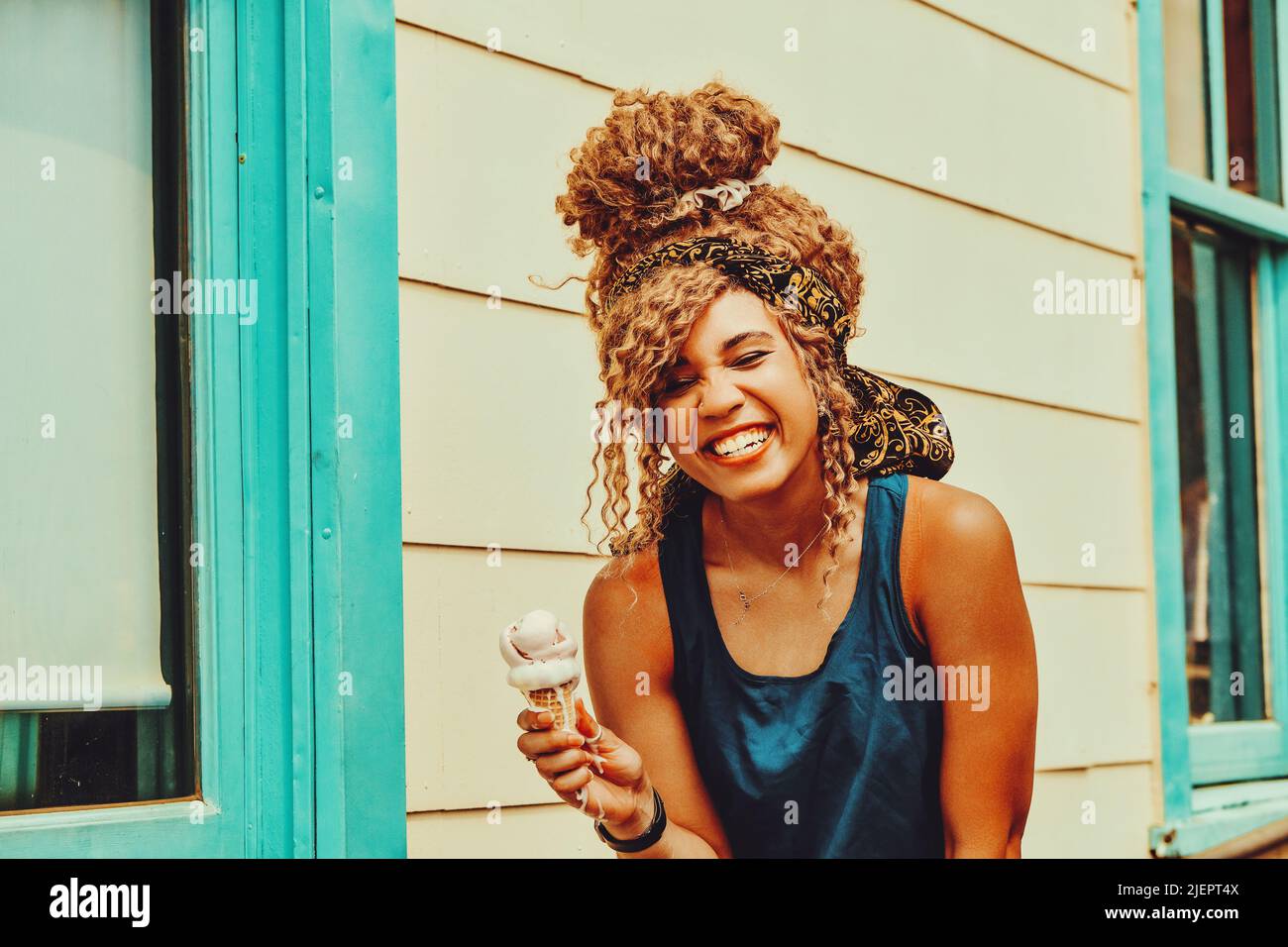 jeune femme adulte cheveux afro souriant manger de la glace à l'extérieur prise de vue estivale Banque D'Images