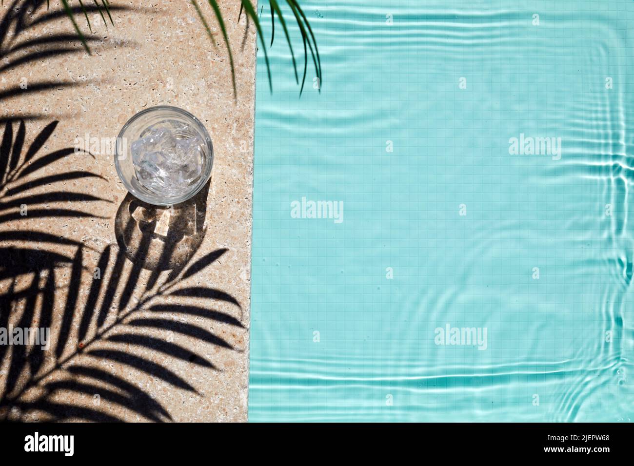 Vue sur la piscine avec verre d'eau et ombre aux palmiers. Concept de vacances d'été Banque D'Images