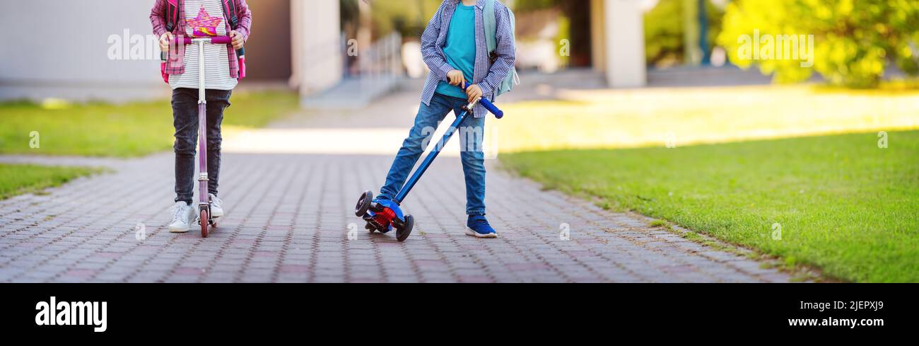 Fille et garçon à cheval de scooters de l'école. Banque D'Images