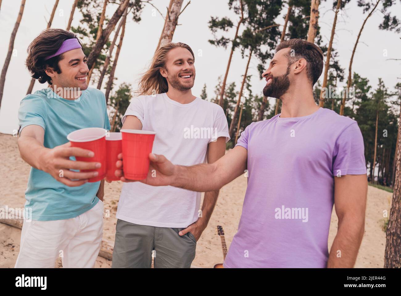 Portrait de trois personnes paisibles satisfaites tenir en plastique Bear Cup dire toast appréciez passe-temps dehors Banque D'Images