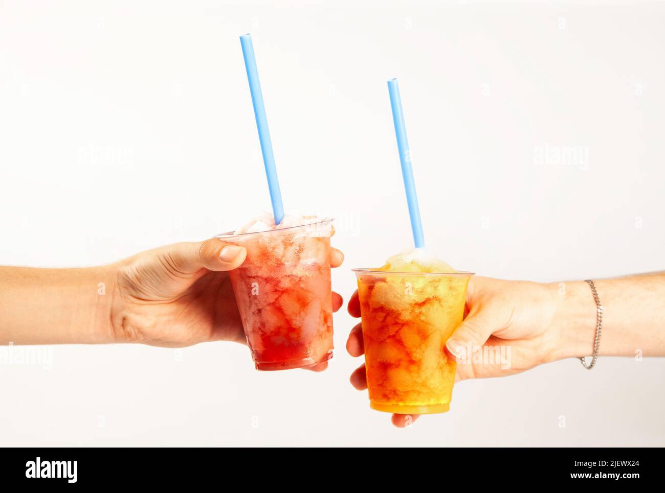Mains tenant deux boissons glacées aromatisées à la slush avec pailles Banque D'Images