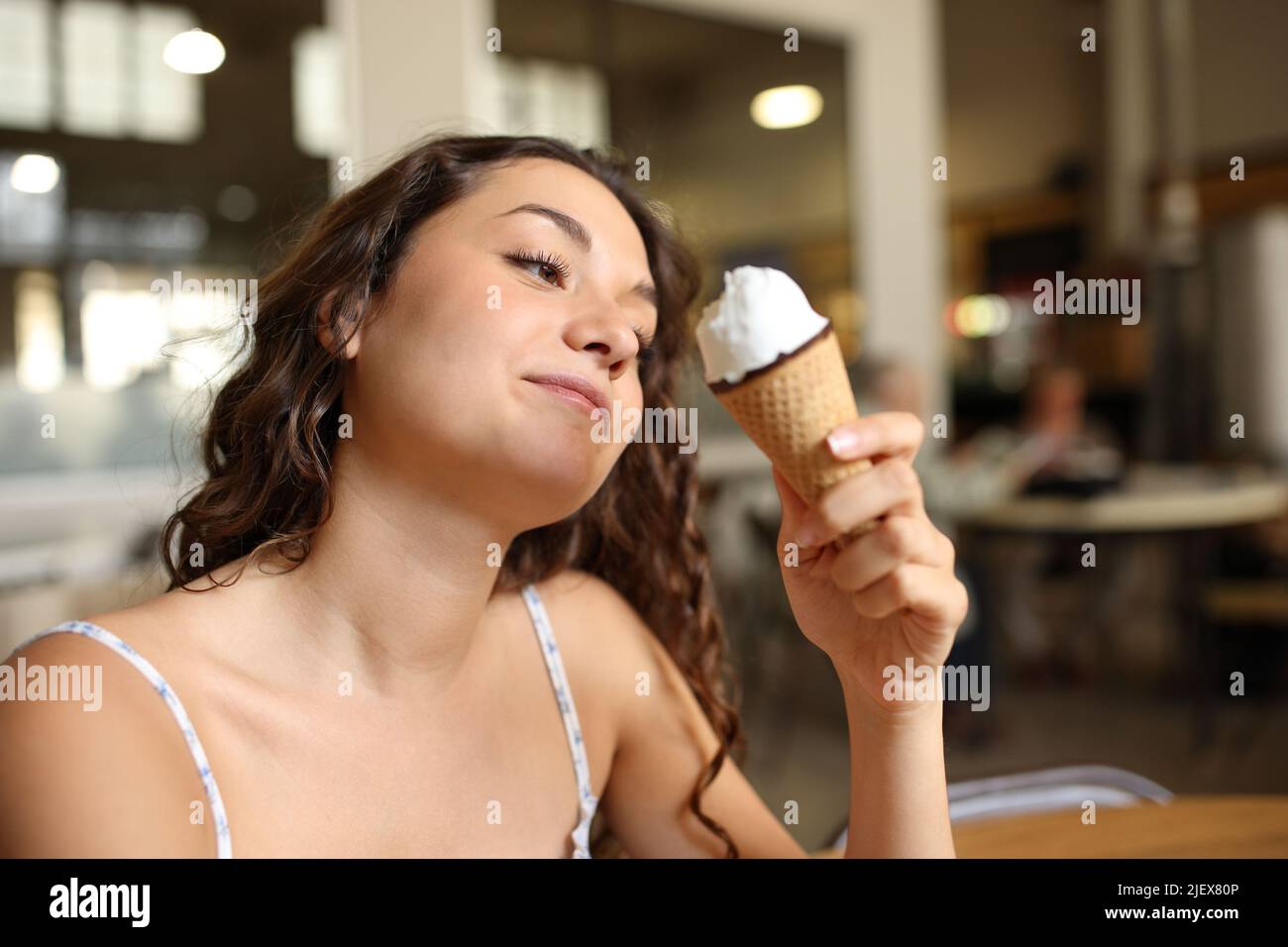 Femme mangeant une glace assise dans un café à l'intérieur Banque D'Images