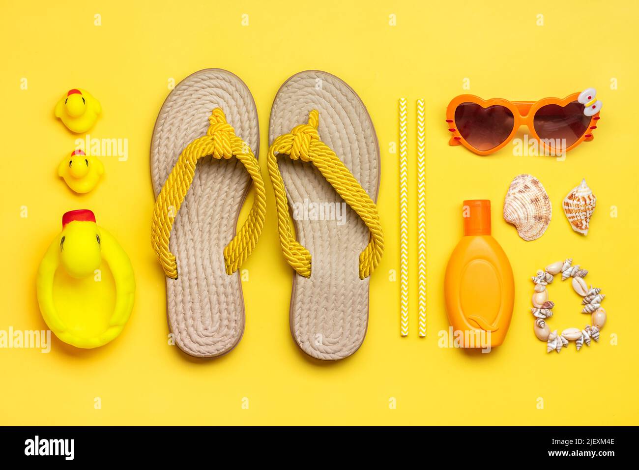 Accessoires de natation - tongs de plage tendance, jouet de canard, bloc de  soleil orange, coeur - lunettes de forme, bracelet de coquillages sur fond  jaune plat Lay Top vue été, voyage,