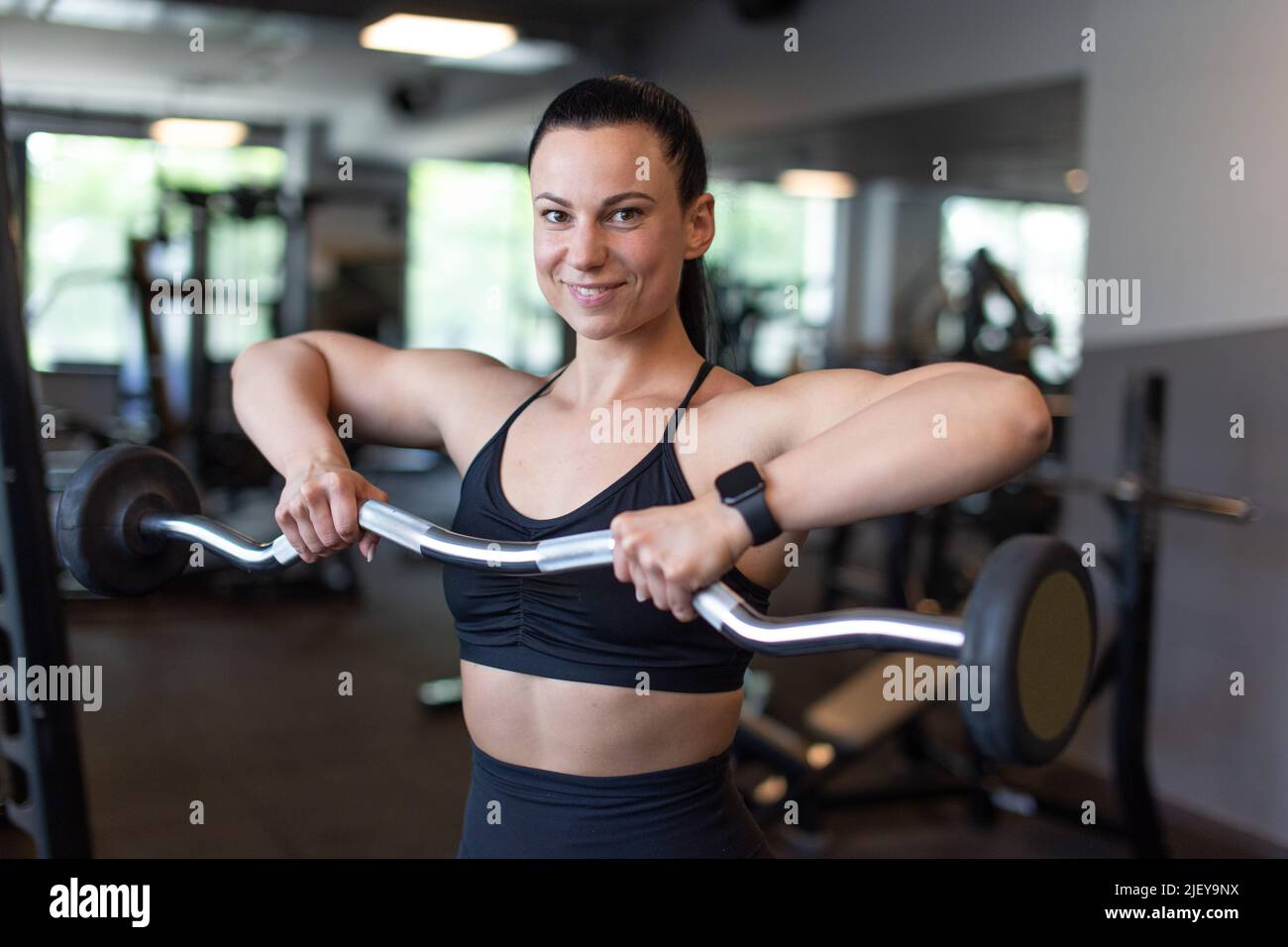 Jeune femme tenant le bar olympique dans la salle de gym, une smae crasseuse Banque D'Images