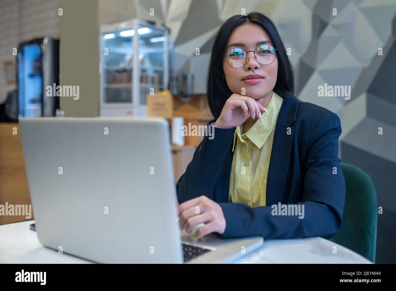 Femme assise à un ordinateur portable regardant de côté Banque D'Images