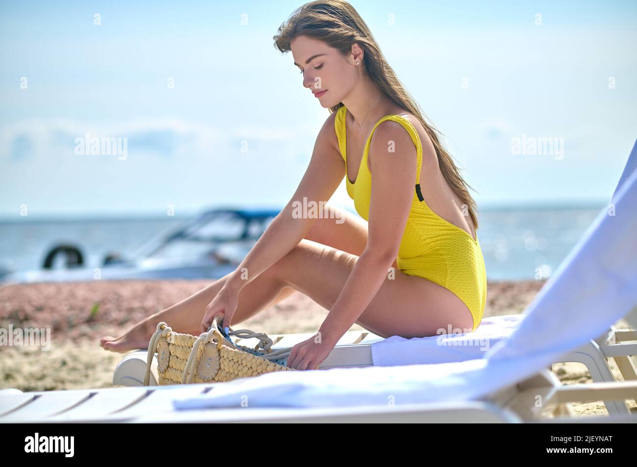 Jeune femme caucasienne aux cheveux longs assise sur le transat Banque D'Images