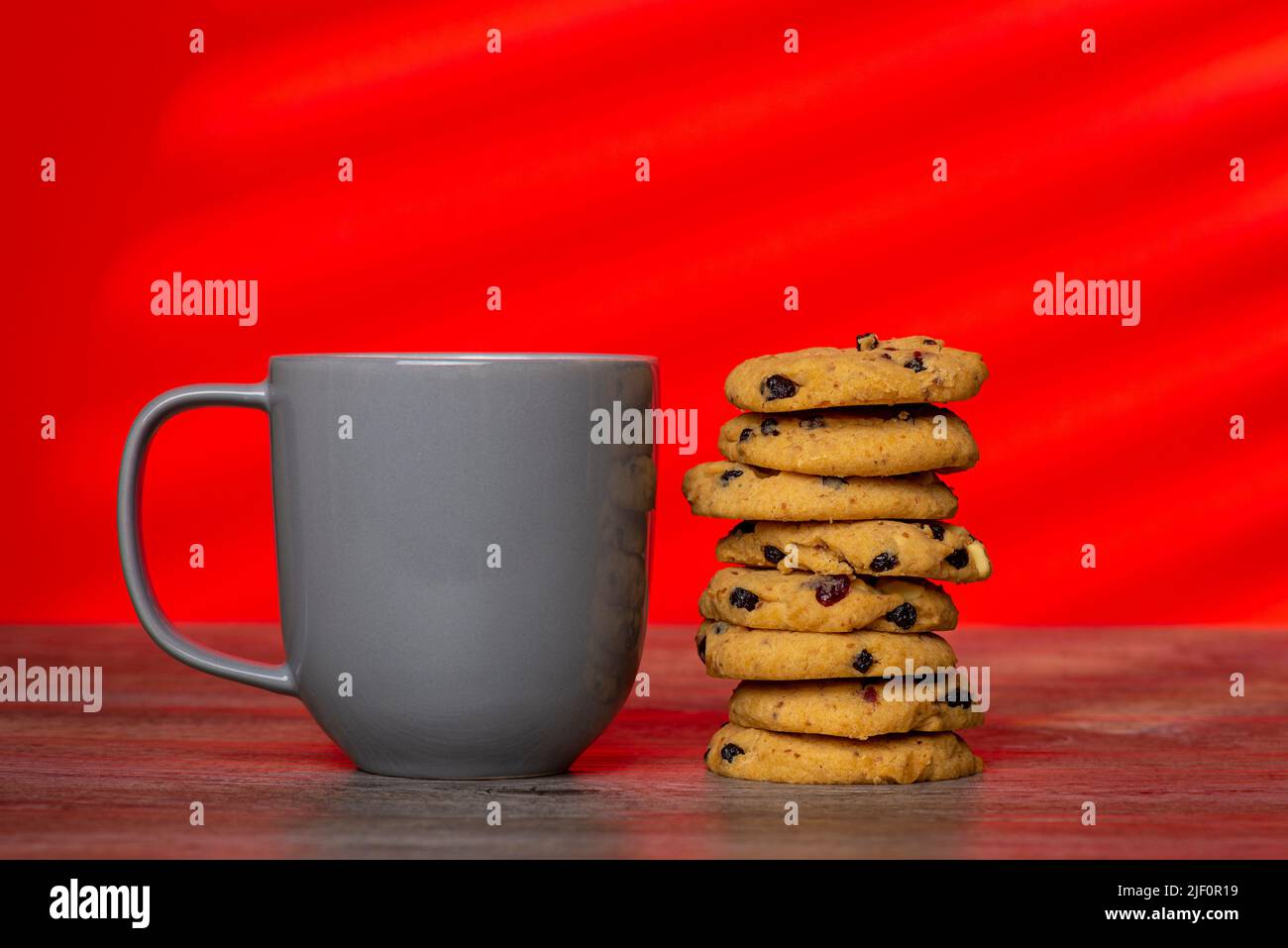 Une pile de biscuits faits maison et une tasse grise sur fond rouge. Banque D'Images