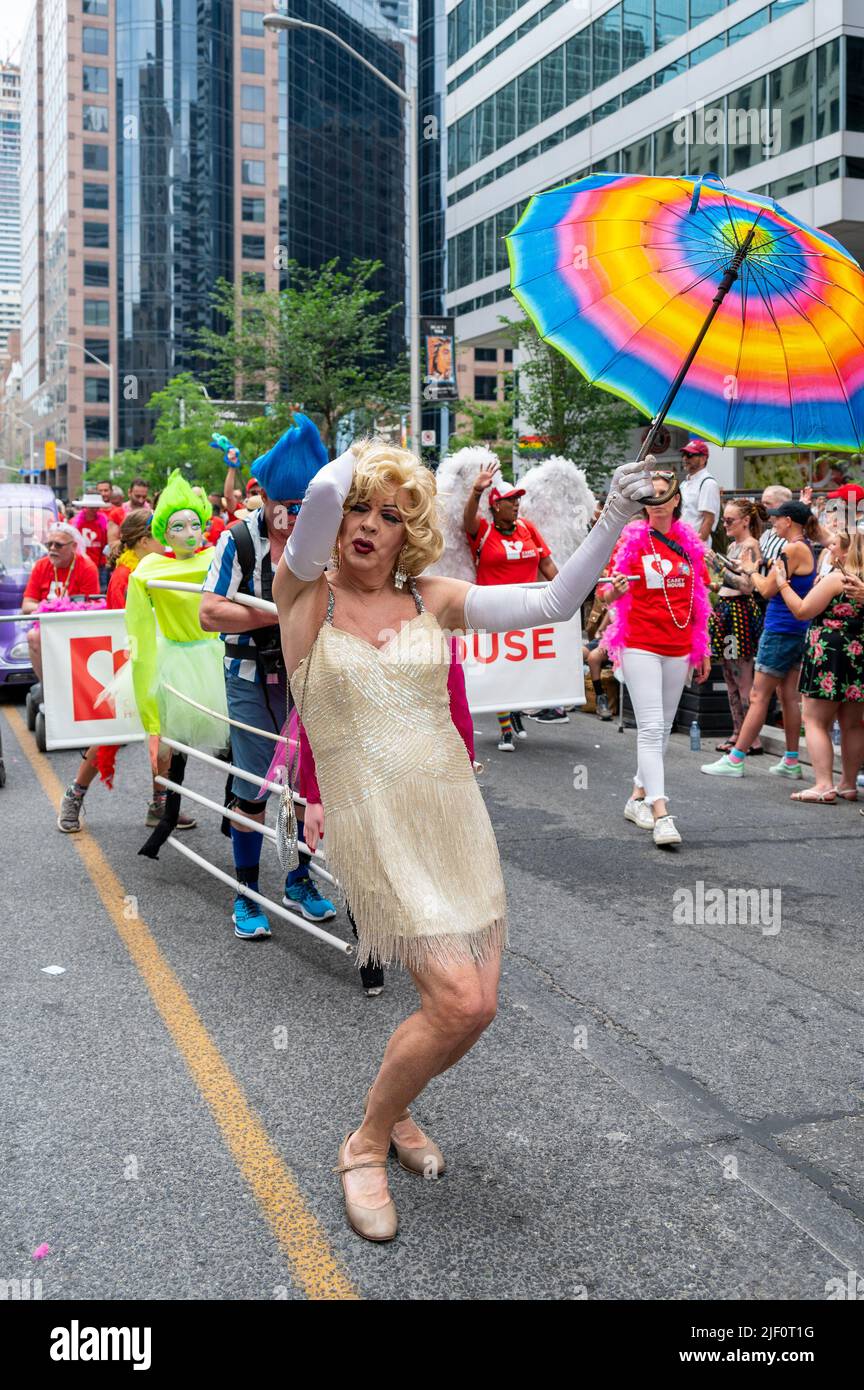 Une personne âgée portant une robe et un parapluie arc-en-ciel marche dans Bloor Street pendant Pride Parade Banque D'Images