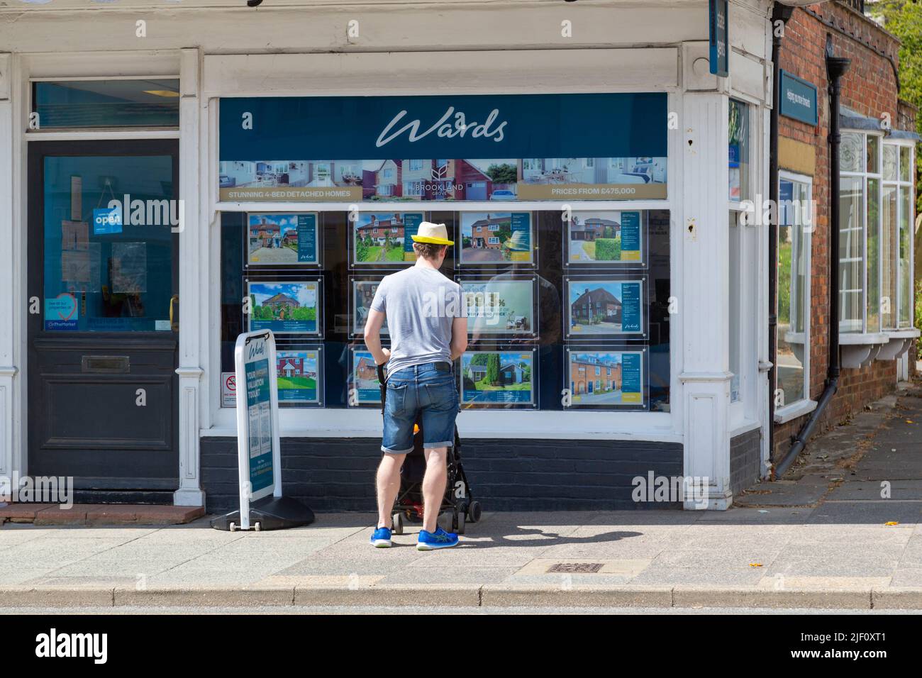 Homme avec poussette regardant une fenêtre d'agent immobilier, pupilles, tenterden, kent, royaume-uni Banque D'Images