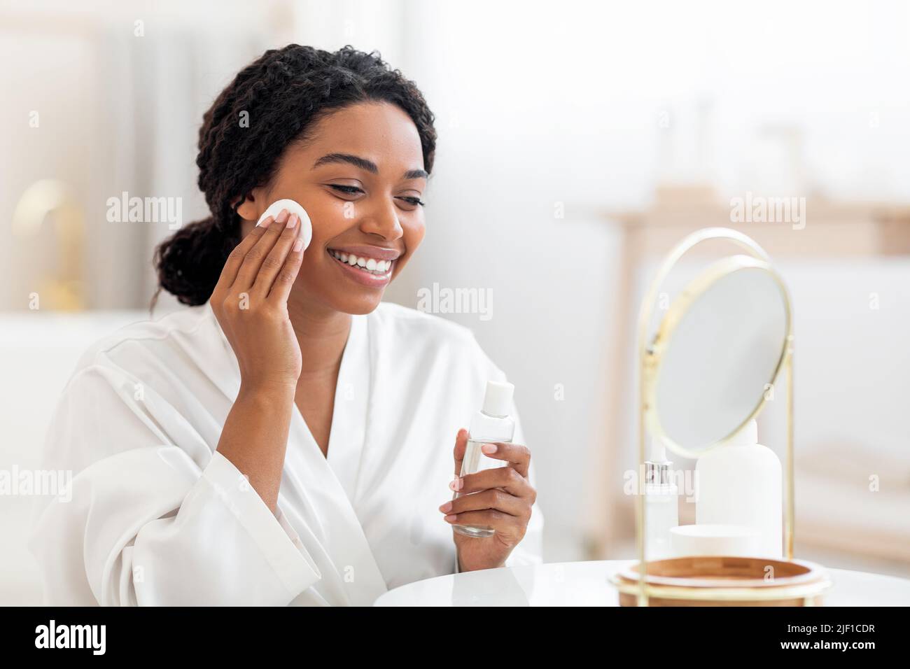 Happy Black Lady utilisant de l'eau micellaire et un tampon de coton pour le nettoyage de la peau Banque D'Images