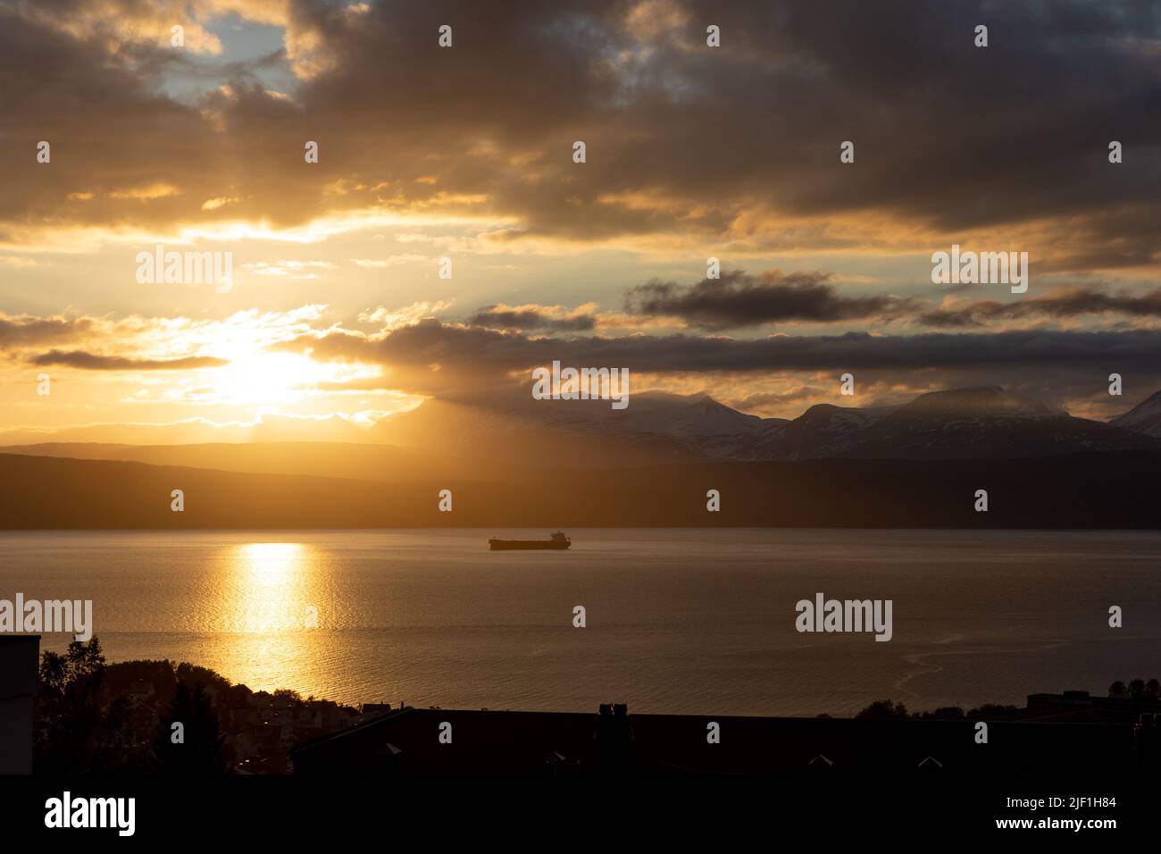 Un gros navire de fret s'approchant de Narvik, dans le nord de la Norvège. Transport du minerai de fer de Kiruna au port libre de glace. Magnifique coucher de soleil et ciel. Banque D'Images