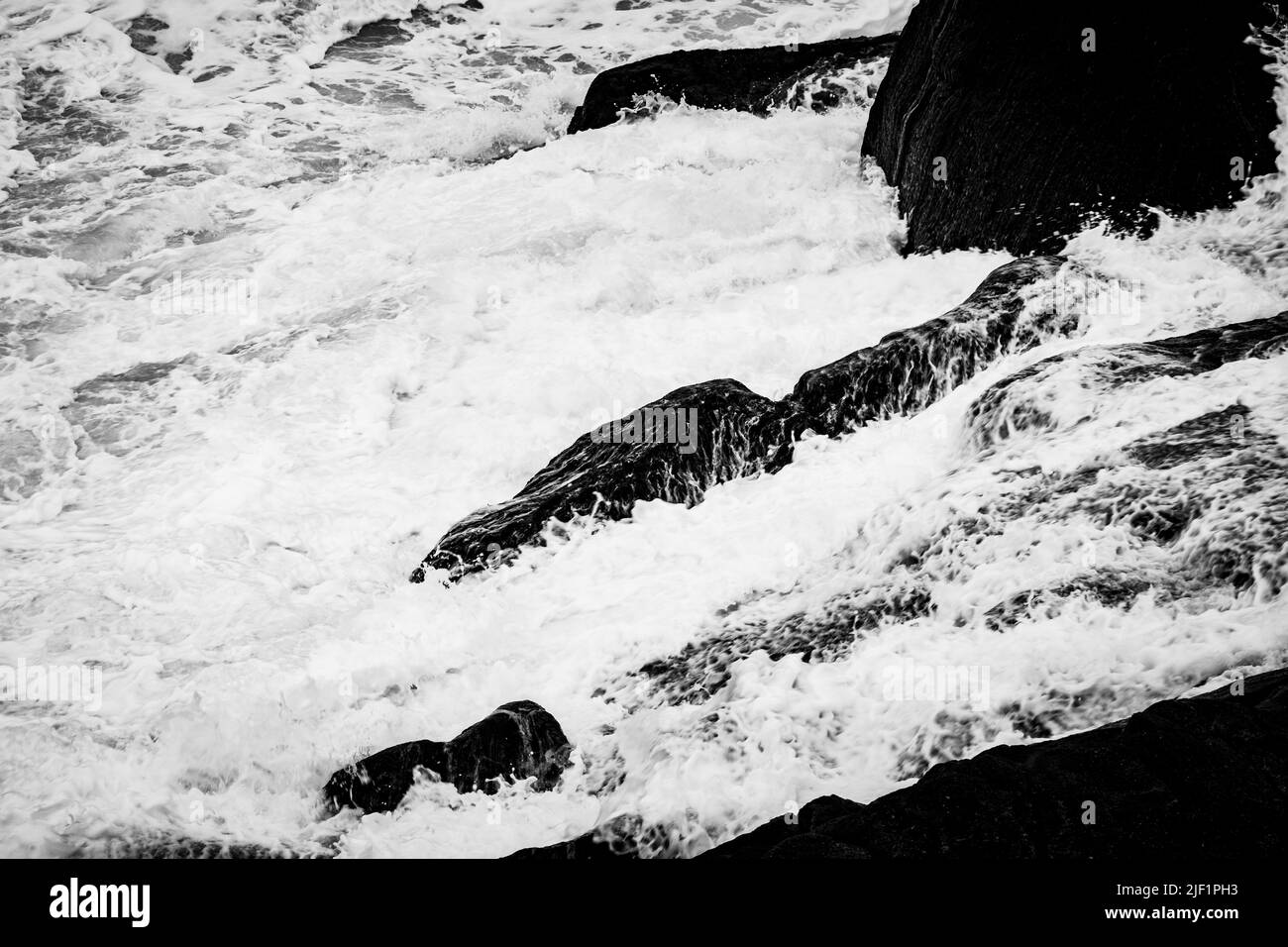 La mousse de mer laiteuse coule au-dessus d'une côte rocheuse en Nouvelle-Écosse. Banque D'Images