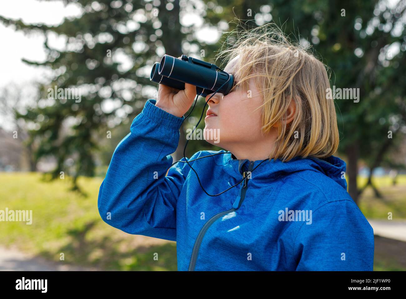 Enfant regardant à travers des jumelles dans le parc. Portrait d'un petit garçon explorant la faune. Observation des oiseaux, randonnée et concept d'aventure. Banque D'Images