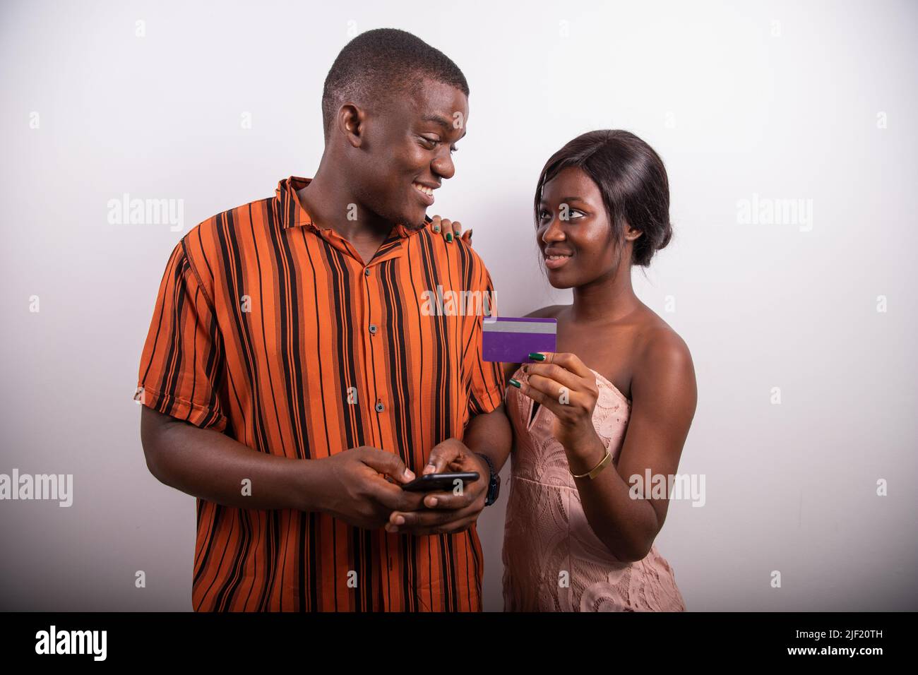 Un garçon et une fille africains font un paiement sur Internet en utilisant une carte de crédit et un smartphone, la technologie en Afrique Banque D'Images