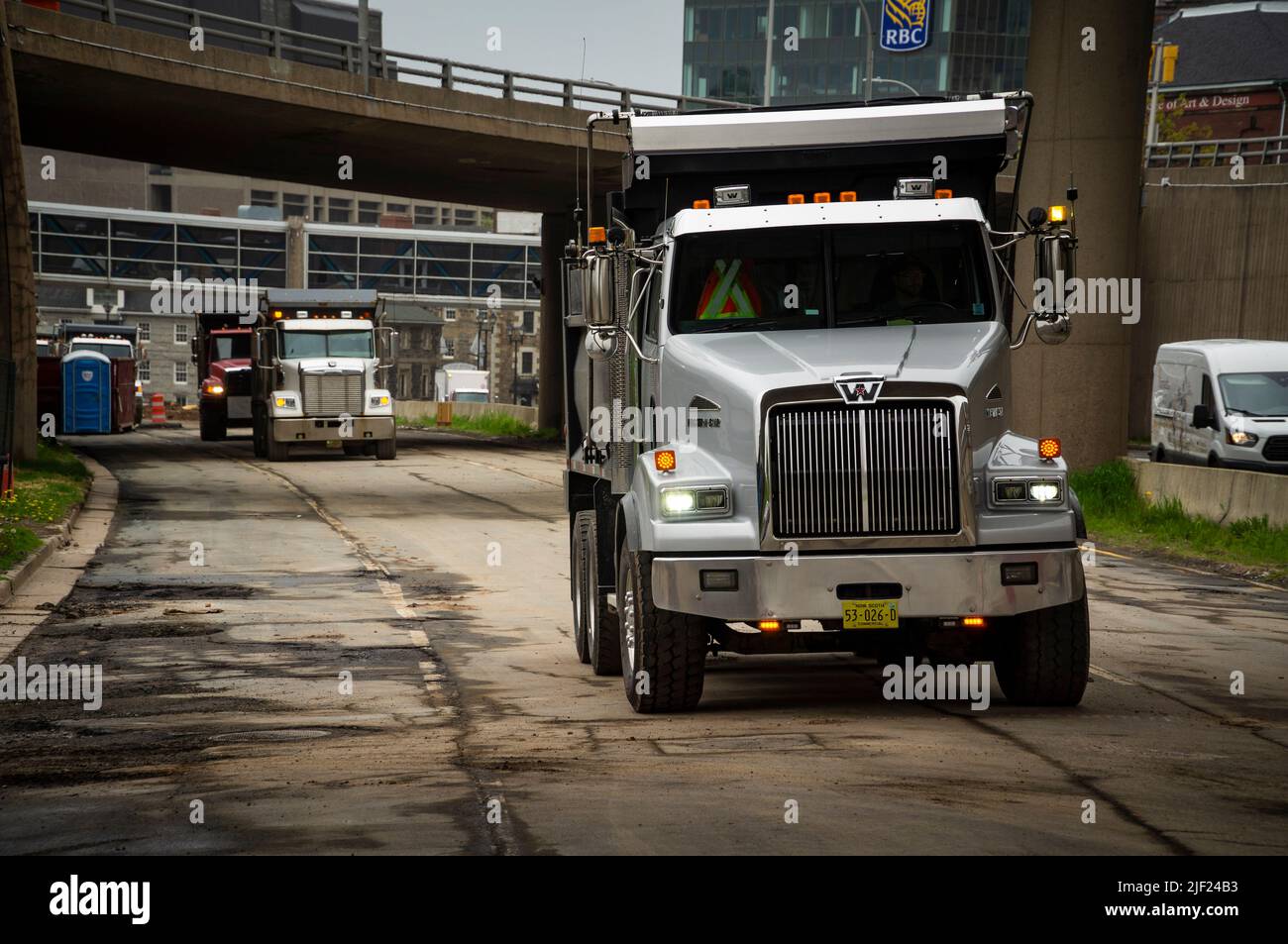Une ligne de camions à benne tandem sur une chaussée sous un passage de roue. Banque D'Images