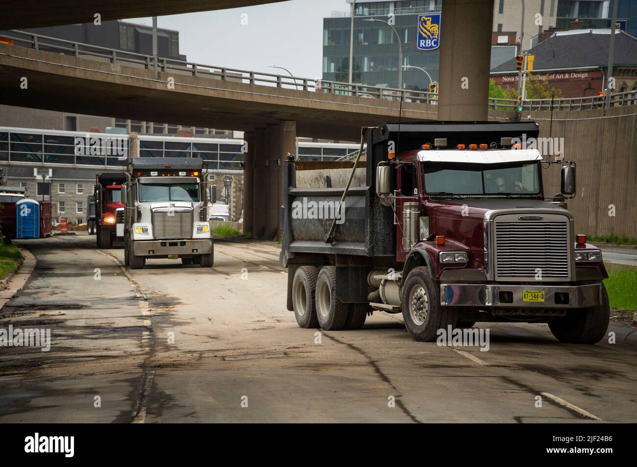 Une ligne de camions à benne tandem sur une chaussée sous un passage de roue. Banque D'Images