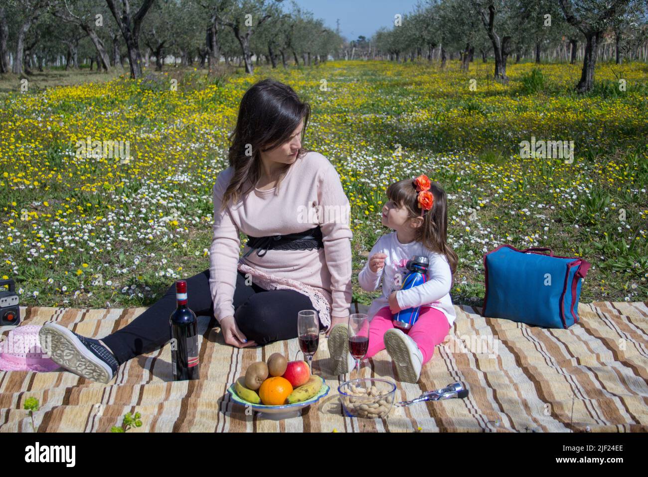 Image d'une mère avec sa fille assise sur un pré fleuri tout en ayant un pique-nique pendant des vacances en Toscane Italie Banque D'Images