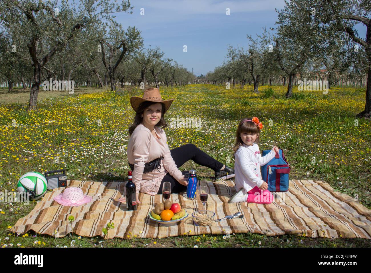 Image d'une mère avec sa fille assise sur un pré fleuri tout en ayant un pique-nique pendant des vacances en Italie Banque D'Images