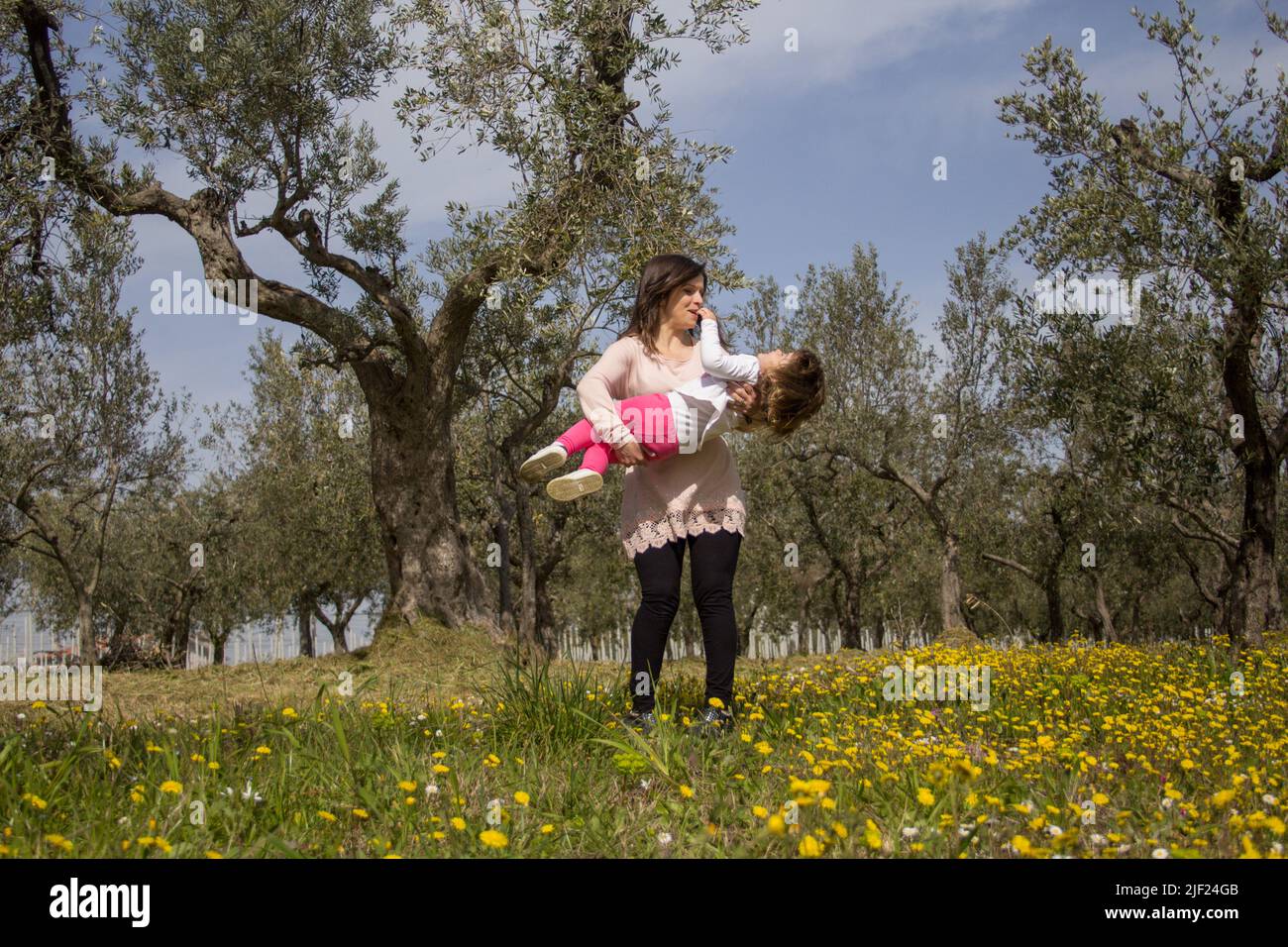Image d'une jeune mère tenant sa fille dans les bras pendant qu'elle joue dans un champ fleuri lors d'un voyage en Toscane Italie Banque D'Images