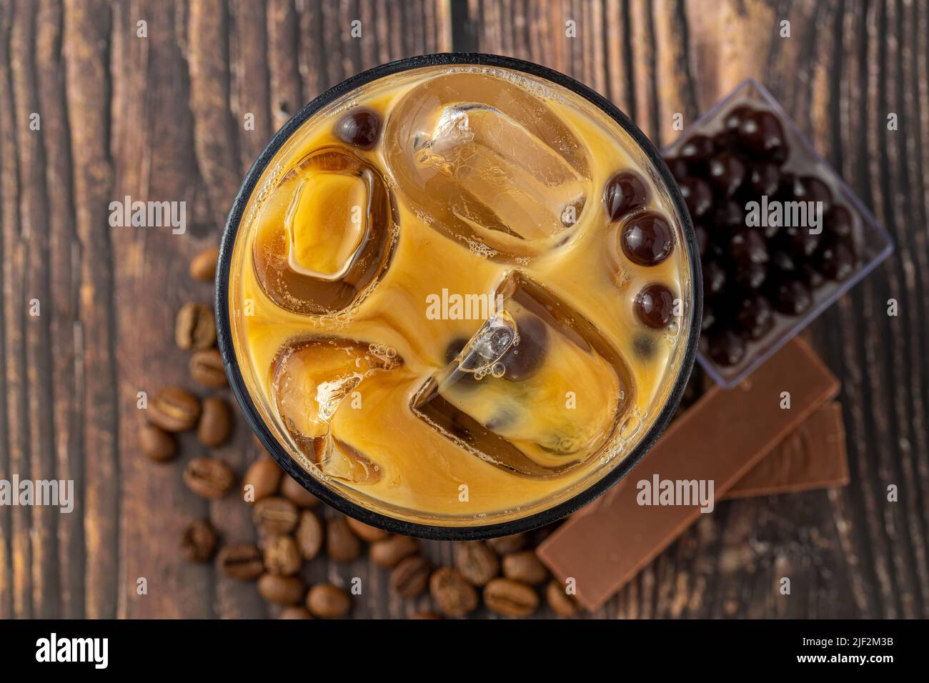 Thé moussant avec café et chocolat dans une tasse de verre sur fond sombre. Banque D'Images