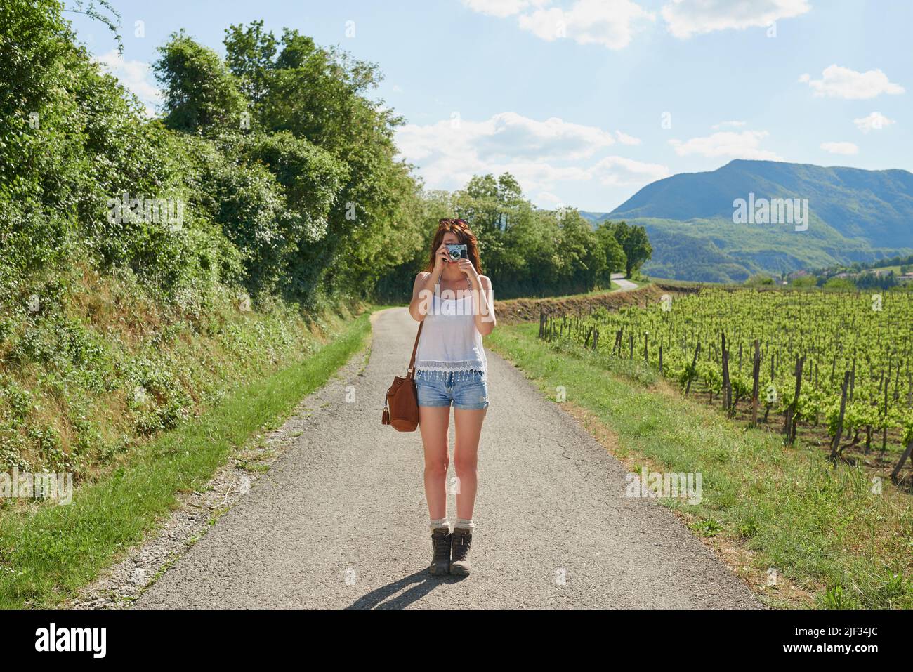 Femme voyageant seule en train de prendre des photos à l'aide de son appareil photo numérique lorsqu'elle est debout sur la route. Jeune femme en vacances seule prenant des photos avec son numérique Banque D'Images