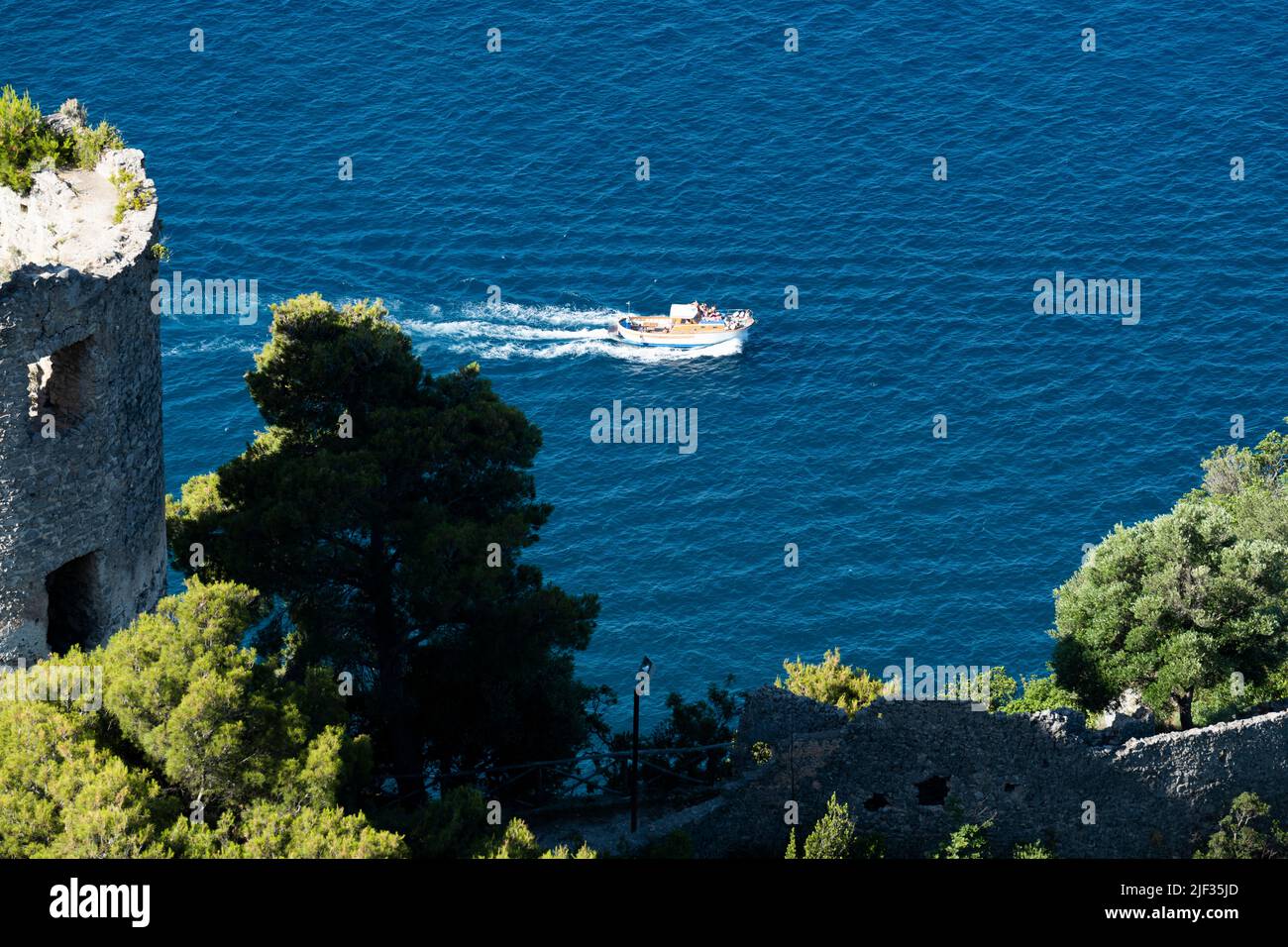 Vue d'en haut, vue imprenable sur un bateau gozzo avec les touristes à bord de la voile sur une eau bleue. Au premier plan, Torre dello Ziro a été défoqué. Banque D'Images