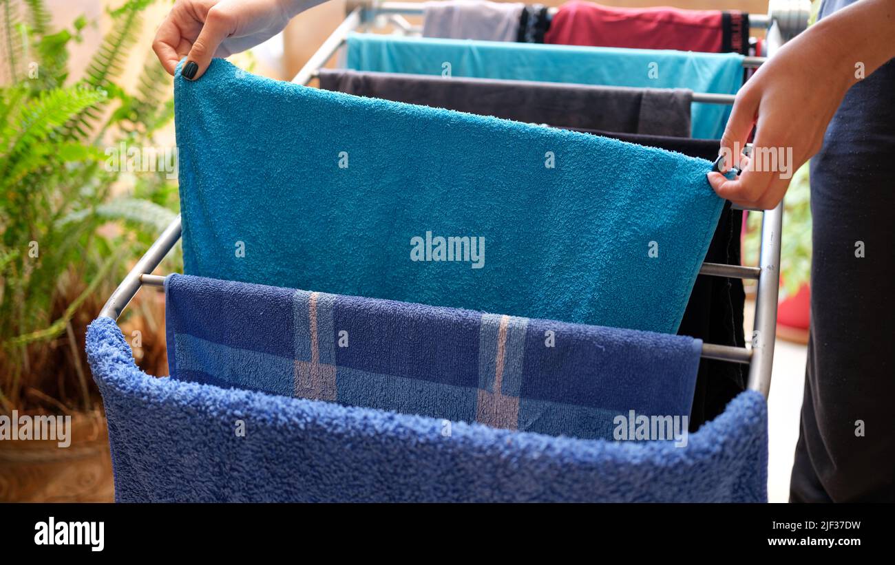 Une femme porte du linge de maison propre et des serviettes sur le sèche-linge à la maison de près Banque D'Images