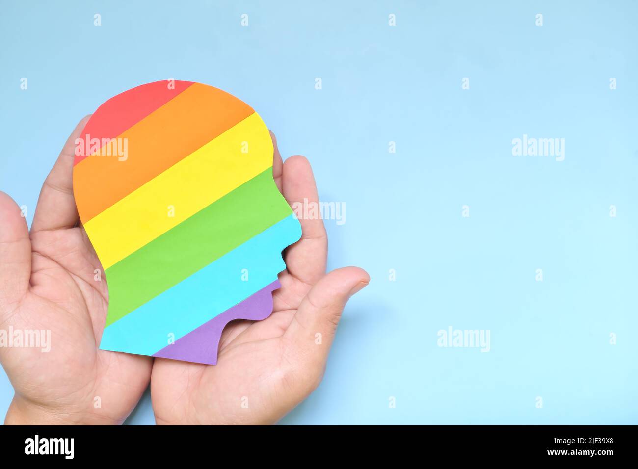 Soutenir la communauté LGBTQIA, l'acceptation, la tolérance et le concept des droits de la personne. Vue du dessus de la main tenant le drapeau LGBT arc-en-ciel couleur profil de la tête humaine. Banque D'Images