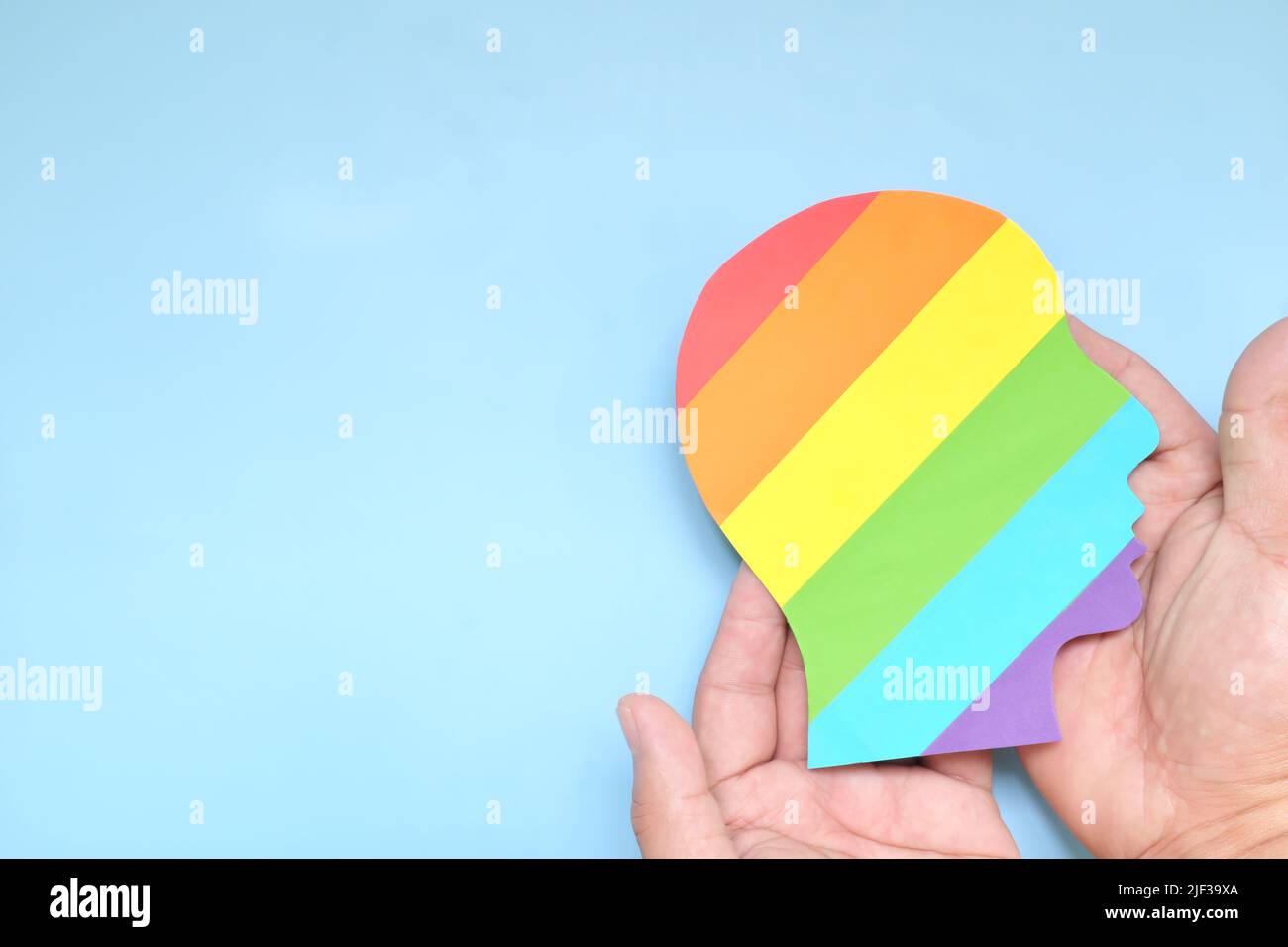 Soutenir la communauté LGBTQIA, l'acceptation, la tolérance et le concept des droits de la personne. Vue du dessus de la main tenant le drapeau LGBT arc-en-ciel couleur profil de la tête humaine. Banque D'Images