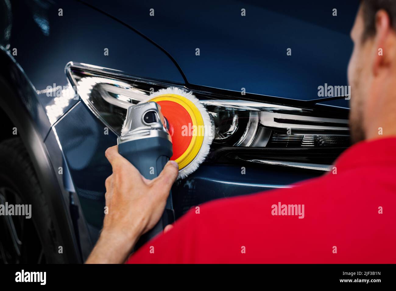 homme à polir le phare de la voiture à l'aide d'une machine à polir. restaurer l'éclairage du véhicule Banque D'Images
