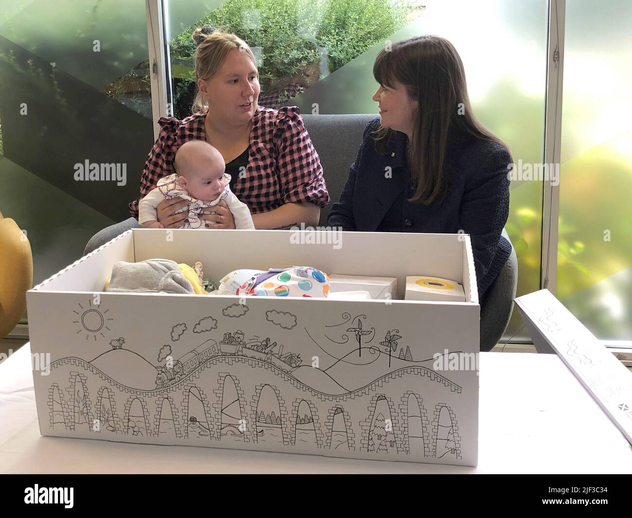 Courtney McLeod et sa fille de quatre mois Addison rencontrent la ministre des enfants Clare Haughey à APS (Groupe) Ecosse à Édimbourg, avec une boîte pour bébé qui est livrée à la mère de chaque nouveau-né quelques semaines avant leur date d'échéance. Environ 222 450 personnes ont été données aux familles depuis août 2017. Banque D'Images