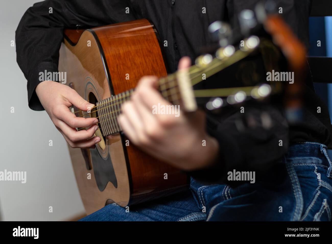 Mains d'un musicien jouant une guitare acoustique avec des cordes métalliques. Passe-temps. Instruments de musique. Mise au point sélective. Gros plan Banque D'Images