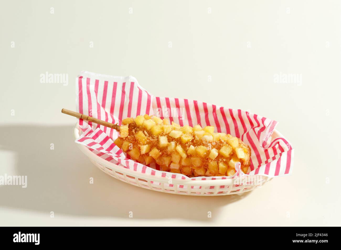 Délicieux croquant Coréen Chunky Potato Corn Dogs avec pâte et pommes de terre frites. Isolé sur fond crème avec espace de copie pour le texte Banque D'Images